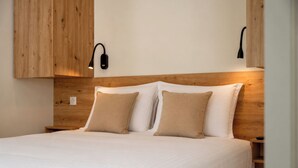 Een bed met een houten hoofdbord, twee bedlampjes en een witte spreideken.