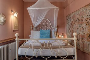 Ein Bett mit Baldachin, eine Wandlampe, ein Wandteppich und eine Heizung.