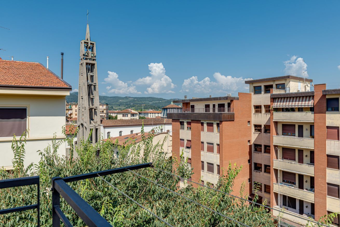 A residential area with a church tower, multi-story buildings, and a clear sky.