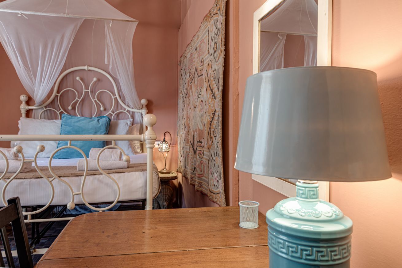 A room with a bed, a table, a lamp, and a wall tapestry.