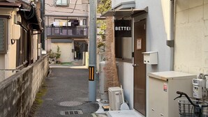 A narrow alleyway with a building labeled 'BETTEI' on the right, a bicycle parked outside, and a manhole cover on the ground. - About a 10-minute walk from Okayama Station / Accommodates up to 6 guests / 1 private parking space available / 3 bedrooms (Okayama City)