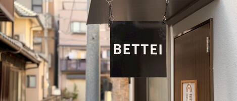 A sign with the word 'BETTEI' hanging from a building.