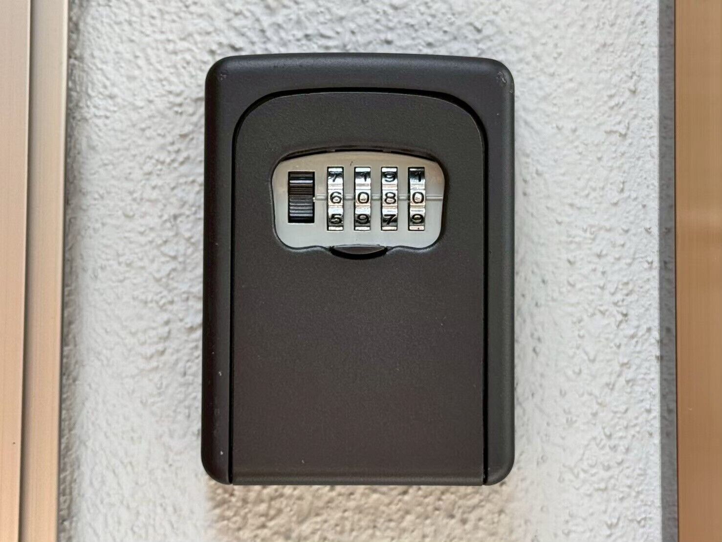 A keypad lock on a textured wall, likely for a door or gate.