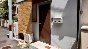 A building with a wooden door, a small step leading to the entrance, and a utility box mounted on the wall. - About a 10-minute walk from Okayama Station / Accommodates up to 6 guests / 1 private parking space available / 3 bedrooms (Okayama City)