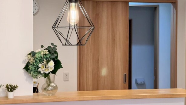 A reception area with a wooden counter, a hanging pendant light, a wall clock, and a door leading to another room. - About a 10-minute walk from Okayama Station / Accommodates up to 6 guests / 1 private parking space available / 3 bedrooms (Okayama City)
