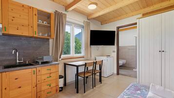 A compact room with a kitchenette, a dining area, a bed, and a bathroom.