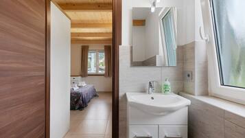 Een moderne badkamer met een witte wasbak, een spiegel en een raam.