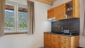 A compact kitchen with wooden cabinets, a built-in oven, and a window with a view of a mountainous landscape.