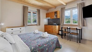 A bedroom with a bed, a desk, and a kitchenette. - Studio 21 at Residence Moulin – for 2 guests (Aymavilles)