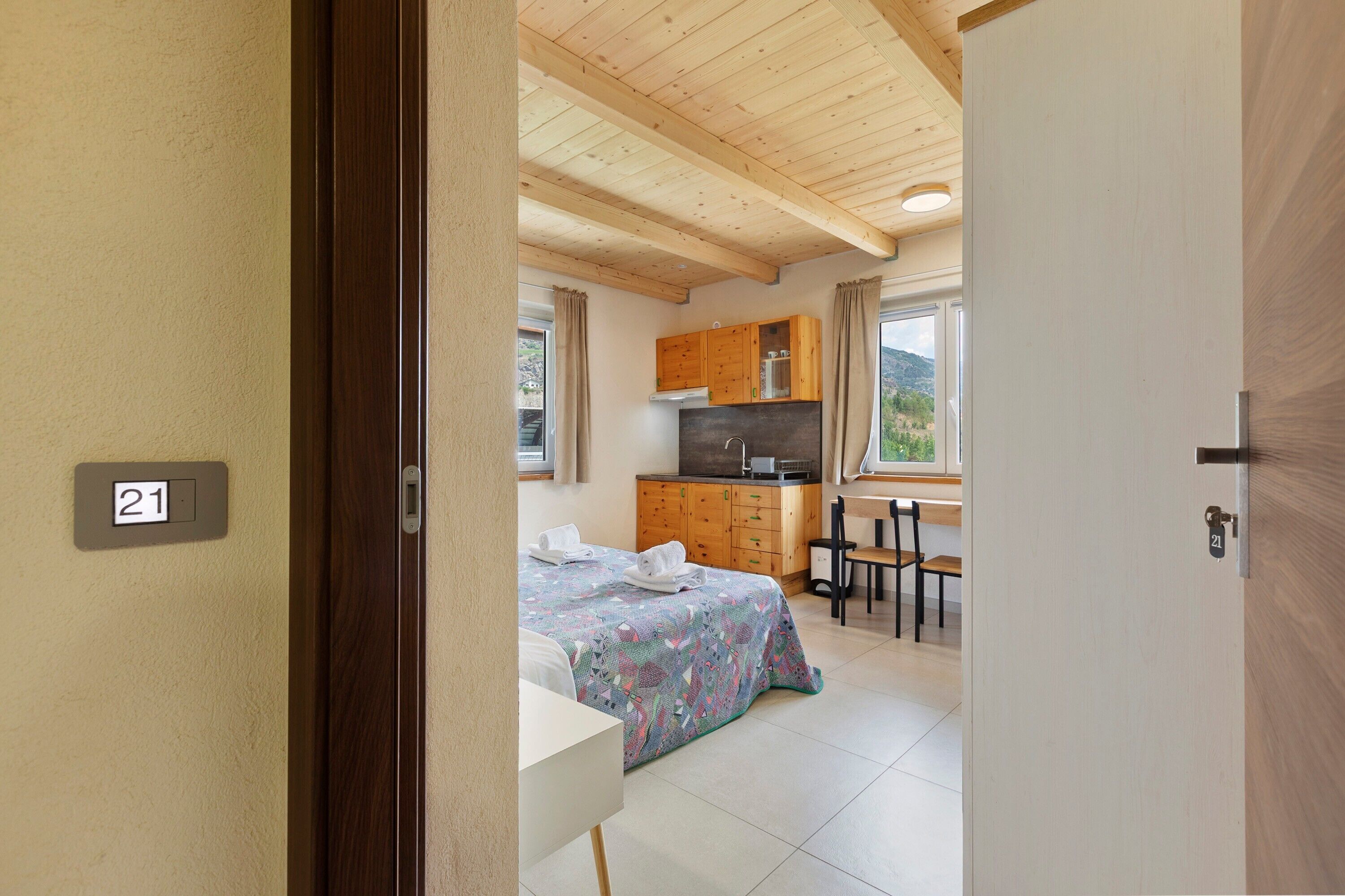 Una habitación con cama, escritorio, silla, kitchenette y baño.