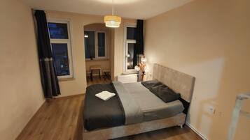 Une chambre à coucher avec un lit, une fenêtre, un radiateur et une lampe.