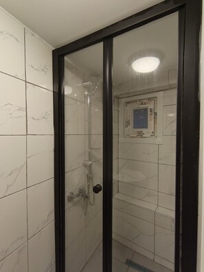 A glass-enclosed shower with a control panel on the wall.