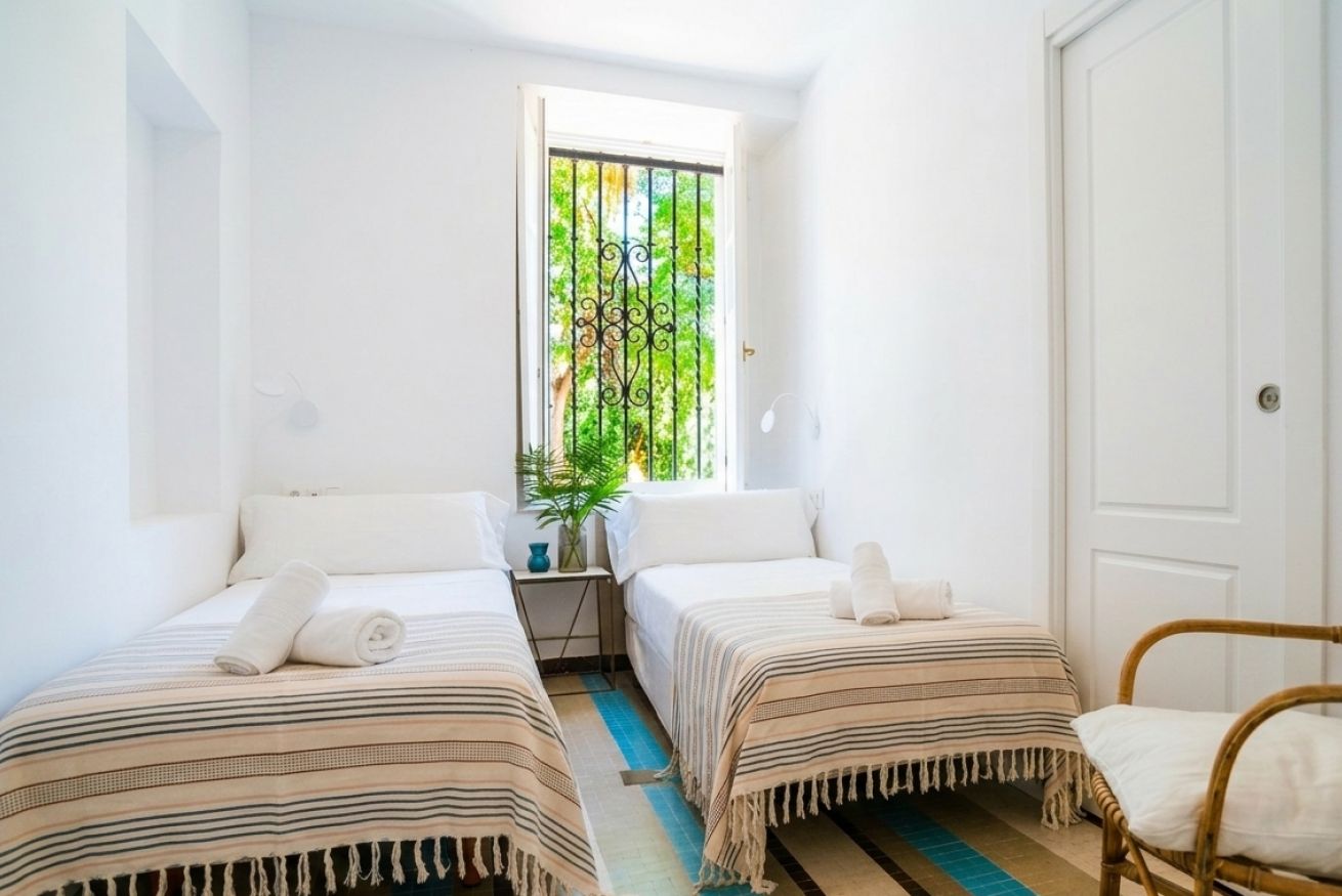 Ein Zimmer mit zwei Betten, einem Fenster mit Blick auf Grünflächen und einer Tür.