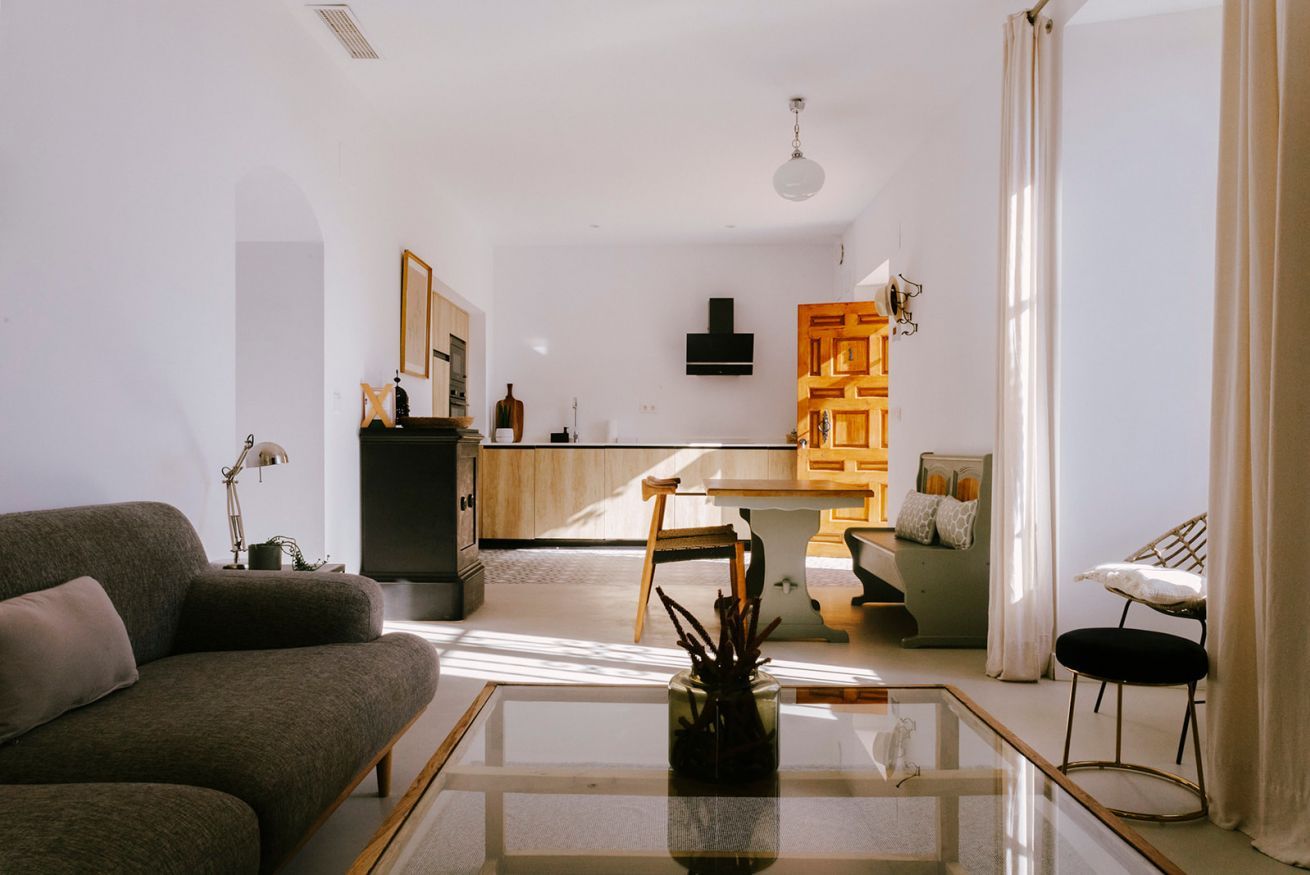 Uma sala de estar moderna com uma mesa de centro de vidro, um sofá e um espaço de jantar com uma cadeira e uma mesa.