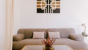Una sala de estar con un sofá, una mesa de centro de vidrio y un jarrón decorativo.