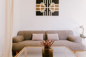 Ein Wohnzimmer mit einer Couch, einem Glastisch und einer dekorativen Vase.