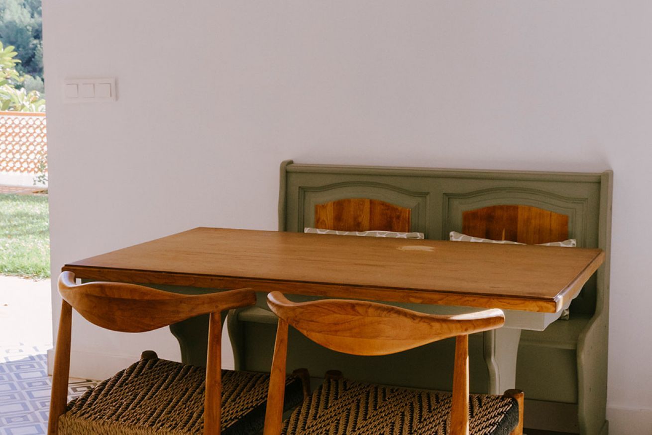Un tavolo da pranzo piccolo con due sedie, una testiera imbottita verde e un tappeto di fibre.