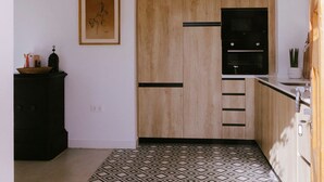 Una cocina compacta con armarios de madera, horno negro y piso estampado.