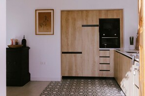Eine kleine Küche mit Holzausstattung, einem schwarzen Backofen und einem gemusterten Boden.