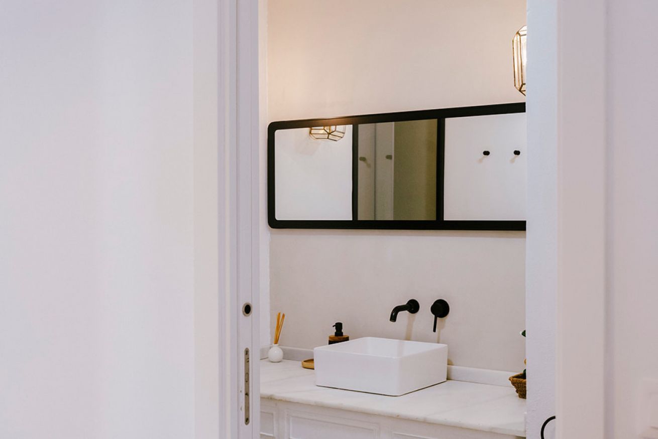 A bathroom with a white sink, a mirror, and a door.