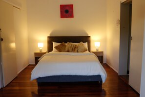 A hotel room with a bed, two bedside tables with lamps, a door, and a red artwork on the wall. - 2- bedroom house in tranquil Rockhampton with Pool (Rockhampton)