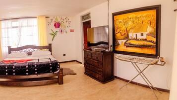 A bedroom with a bed, a dresser, a television, and a painting on the wall.