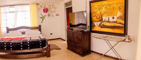A bedroom with a bed, a dresser, a television, and a painting on the wall.