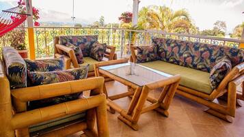 A balcony with a sofa set, a table, and a hanging chair.