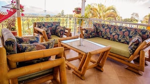 A balcony with a sofa set, a table, and a hanging chair. - Meraki is a Luxury Villa with pool, jacuzzi & Stunning Mountain Views (Quindío)