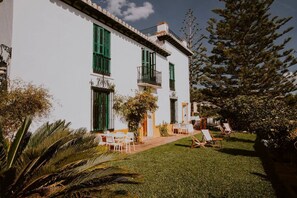 A white building with green shutters, a balcony, and a lawn with chairs. - Hacienda Clavero Two Garden Apartment (Málaga)