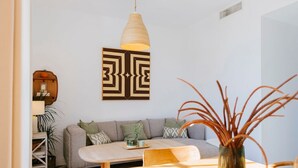 Ein stilvolles Wohnzimmer mit einer Couch, einem Holztisch, einer Pendelleuchte und einer Wanddekoration.