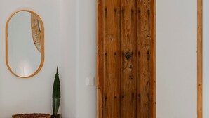 Ein Zimmer mit Holztür, rundem Spiegel mit Zierrahmen und einer Topfpflanze.