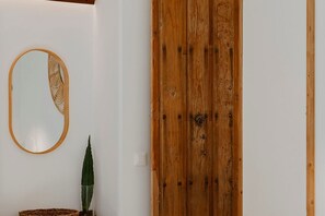 A room with a wooden door, a round mirror with a decorative frame, and a potted plant. - Hacienda Clavero Two Garden Apartment (Málaga)