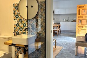 A modern bathroom with a toilet, sink, and mirror. - Hacienda Clavero Three Patio Apartment: (Málaga)