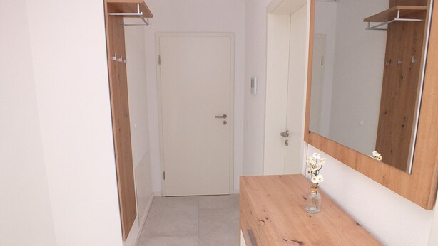 Un pasillo con un aparador de madera, un espejo y una puerta.