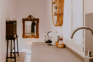 A hallway with a mirror, a small table with a basket, and a wall-mounted light fixture. - Hacienda Clavero Four Garden Apartment: (Málaga)
