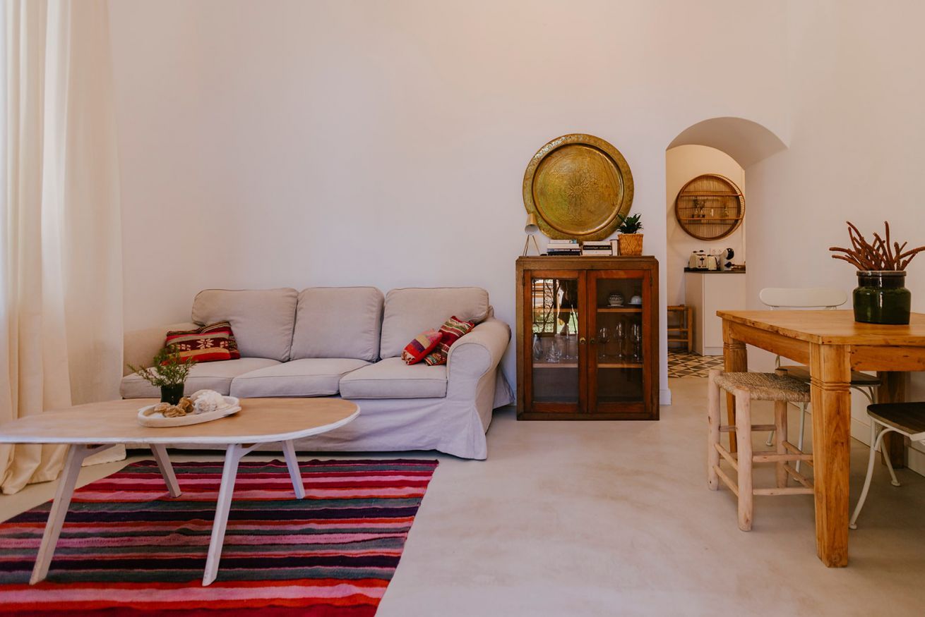 Ein Wohnzimmer mit einer Couch, einem Couchtisch, einem Schrank und einem Esstisch mit Stühlen.