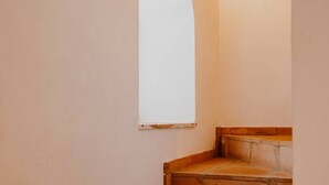 Una escalera estrecha con una pared blanca y una ventana a la derecha.