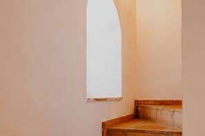 Eine enge Treppe mit weißer Wand und einem Fenster auf der rechten Seite.