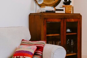 Ein Zimmer mit einer Couch, einem Holzschrank mit Glastüren und einem gemusterten Zierkissen.