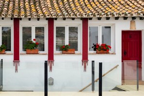 A building with a tiled roof, red columns, and windows with flower boxes. - Hacienda Clavero Five Deluxe Apartment: (Málaga)