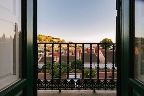 Ein Balkon mit schmiedeeisernem Geländer mit Blick auf eine Wohngegend mit Häusern und Bäumen.
