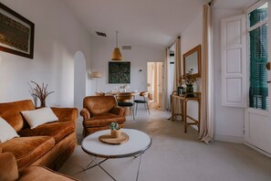 Ein Wohnzimmer mit braunem Sofa, einem runden Couchtisch und einem Essbereich im Hintergrund.