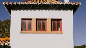 Un edificio blanco con techo plano y una pequeña ventana con marcos rojos.