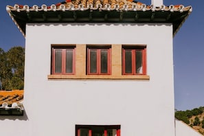 Ein weißes Gebäude mit flachem Dach und einem kleinen Fenster mit roten Rahmen.