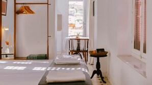 Habitación de hotel con cama, una mesita con una cesta, una silla y ventana con vistas.