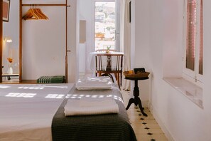 Ein Hotelzimmer mit einem Bett, einem kleinen Tisch mit einem Korb, einem Stuhl und einem Fenster mit Blick.