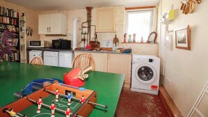 Cocina compacta con lavadora, una mesa y una mesa de fútbol, además de un ventanal con vistas.