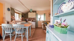 A cozy kitchen with a dining table, chairs, and a refrigerator. - The Granary (Truro)