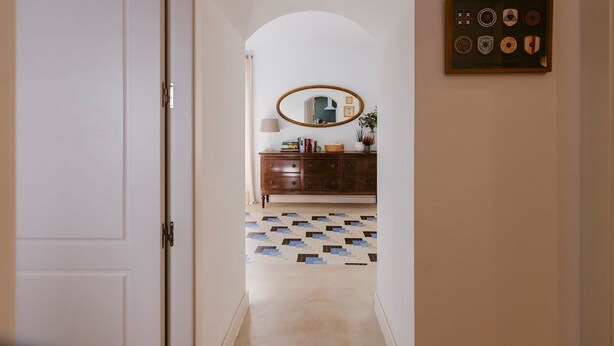 A hallway with a white door, a wooden cabinet, a mirror, and a framed collection of plates on the wall. - Hacienda Clavero Seven Deluxe Apartment: (Málaga)